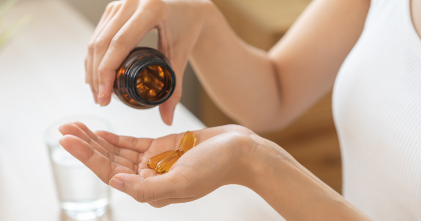 Eine Frau schüttet mehrere Vitamin C Präparat-Kapseln aus einer braunen Medikamentenflasche in die Hand.